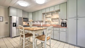 Una cocina moderna con una isla central, armarios blancos y electrodomésticos de acero inoxidable.