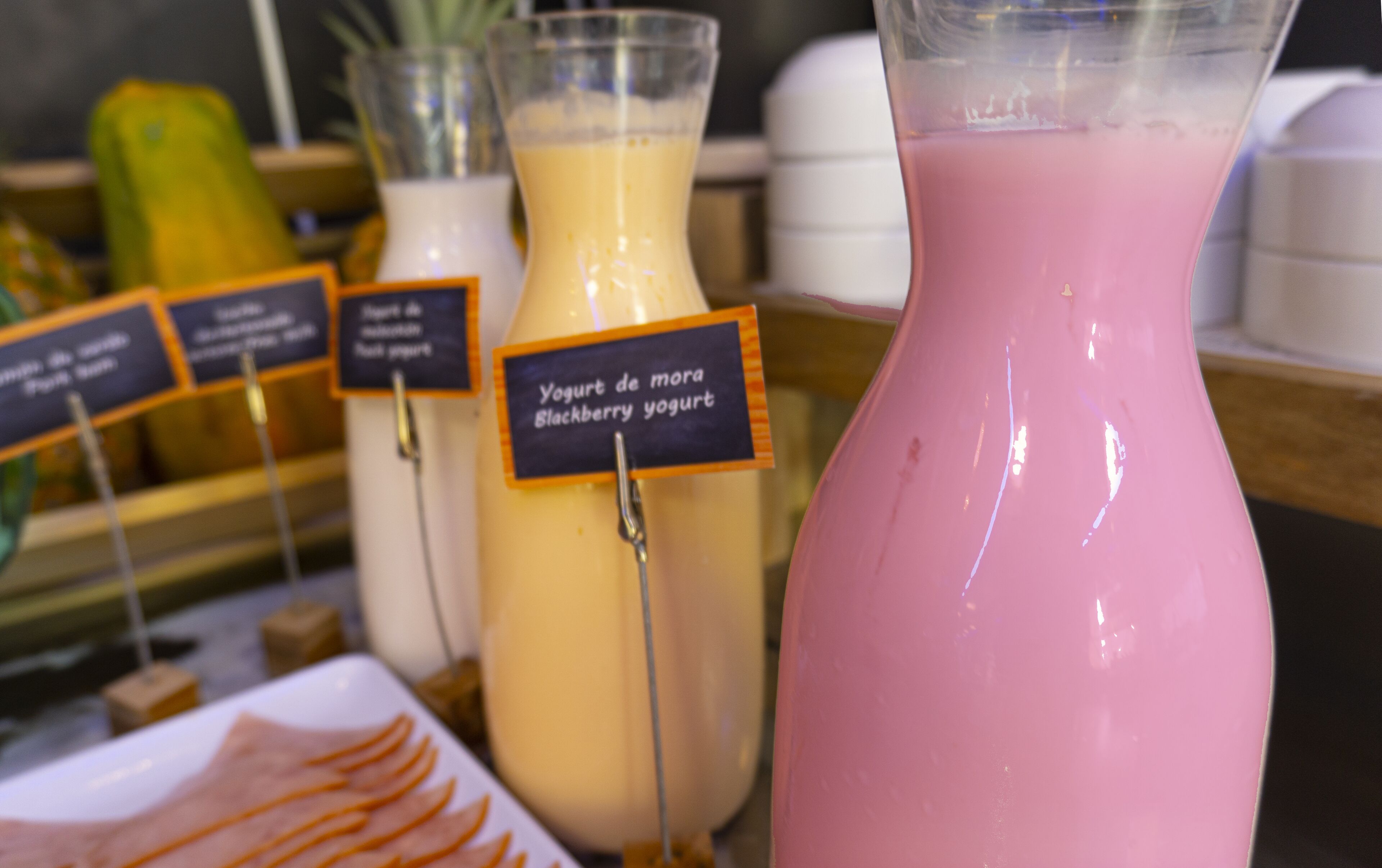 A selection of yogurt drinks in various colors, each labeled with a blackboard sign.