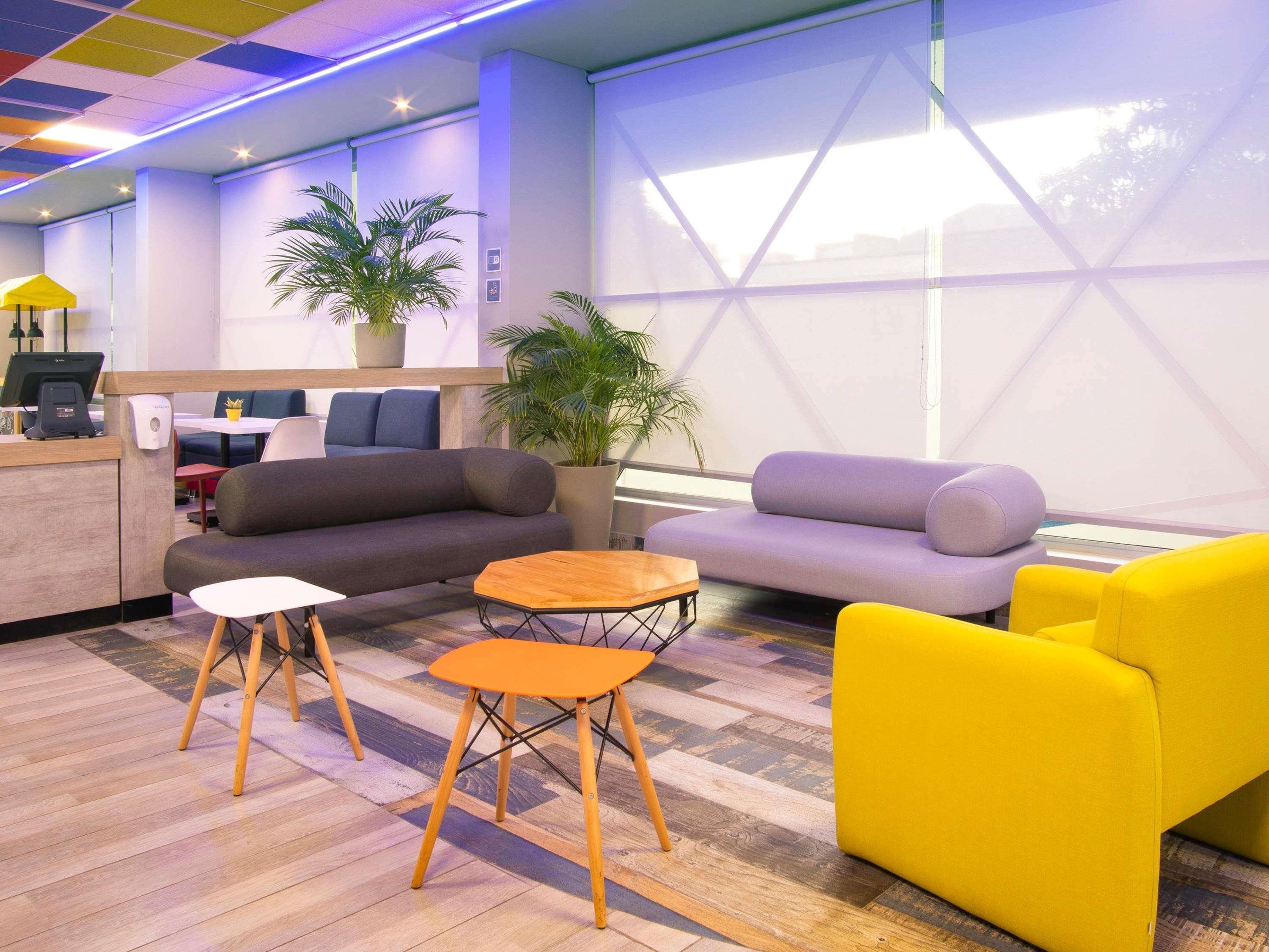 A modern reception area with a sofa, chairs, a small table, and a counter with a computer.