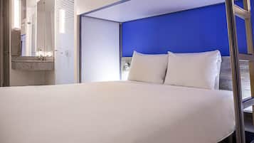 Una camera d'albergo moderna con un letto grande, un bagno con uno specchio e una parete decorata in blu.