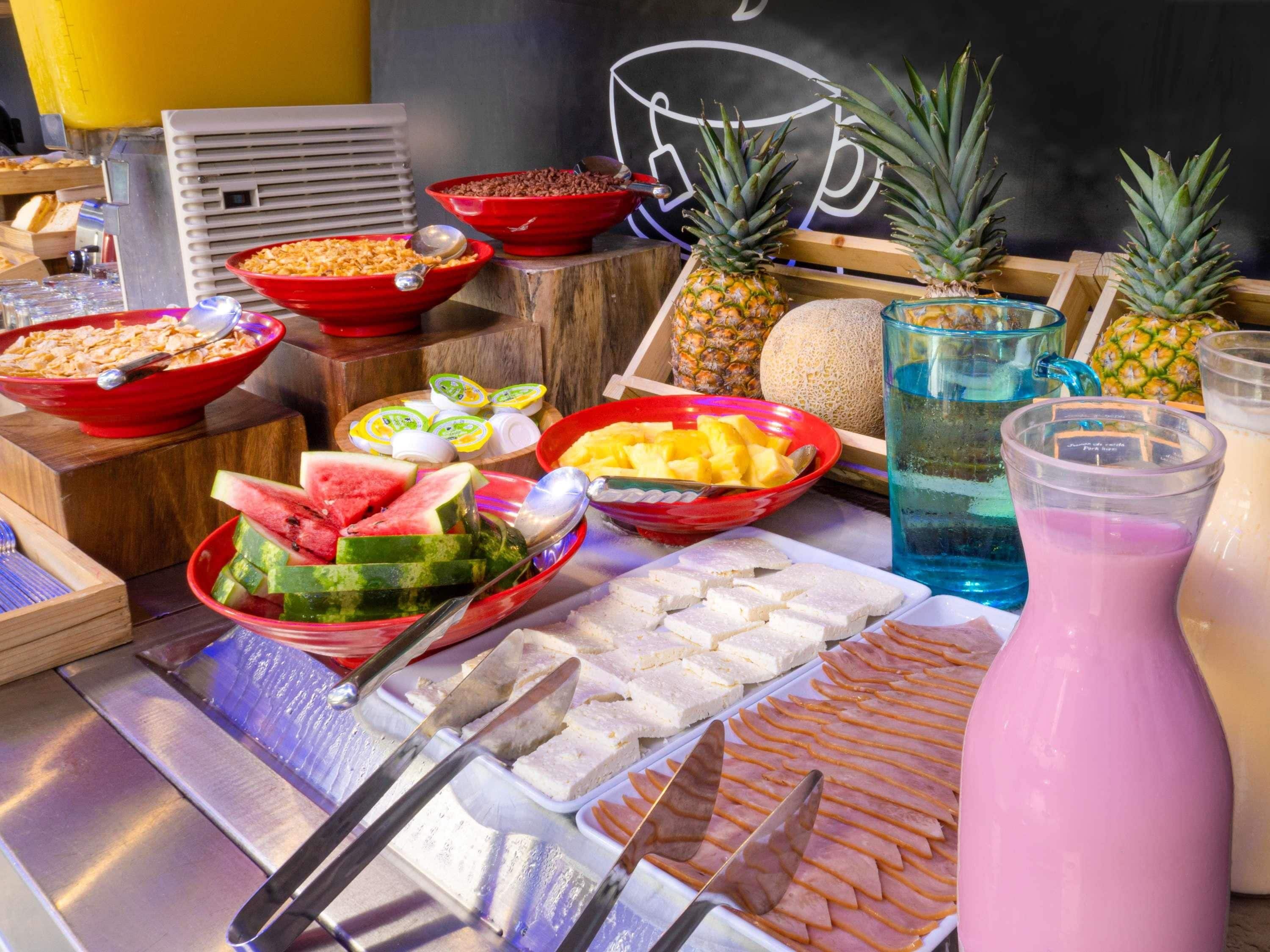 Un bufé con diferentes opciones de comida, incluyendo frutas, verduras y bebidas.