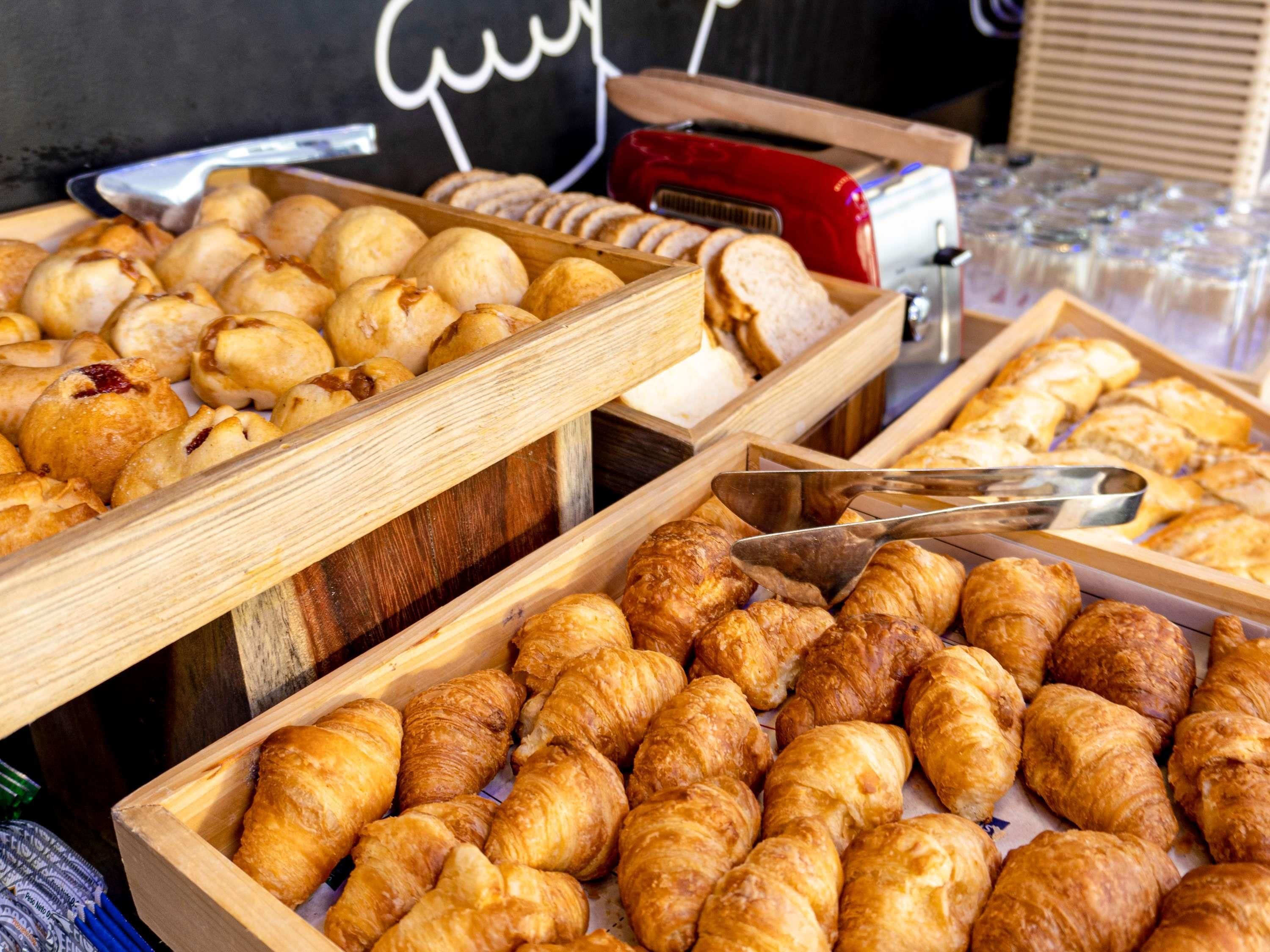 Variedad de productos de repostería expuestos en bandejas de madera, incluyendo cruasanes y otros pasteles.