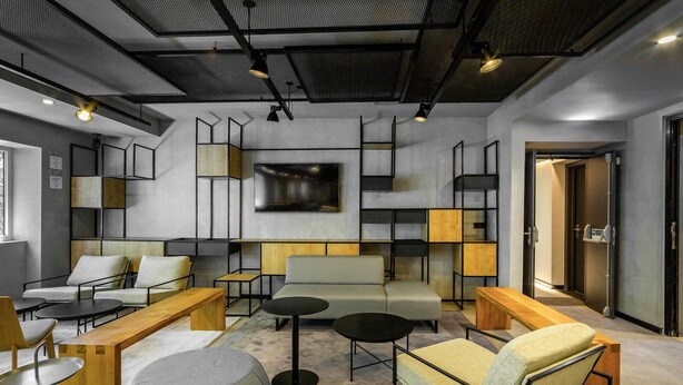 A modern lounge area with sofas, tables, and a large TV screen.