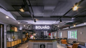 A modern bar area with a central counter, bar stools, and a sign reading "BOLHAO".