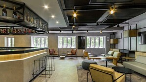 A modern bar area with a counter, seating, and a large window providing natural light.