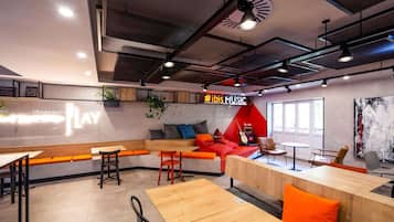 A modern co-working space with a seating area, tables, and a guitar.