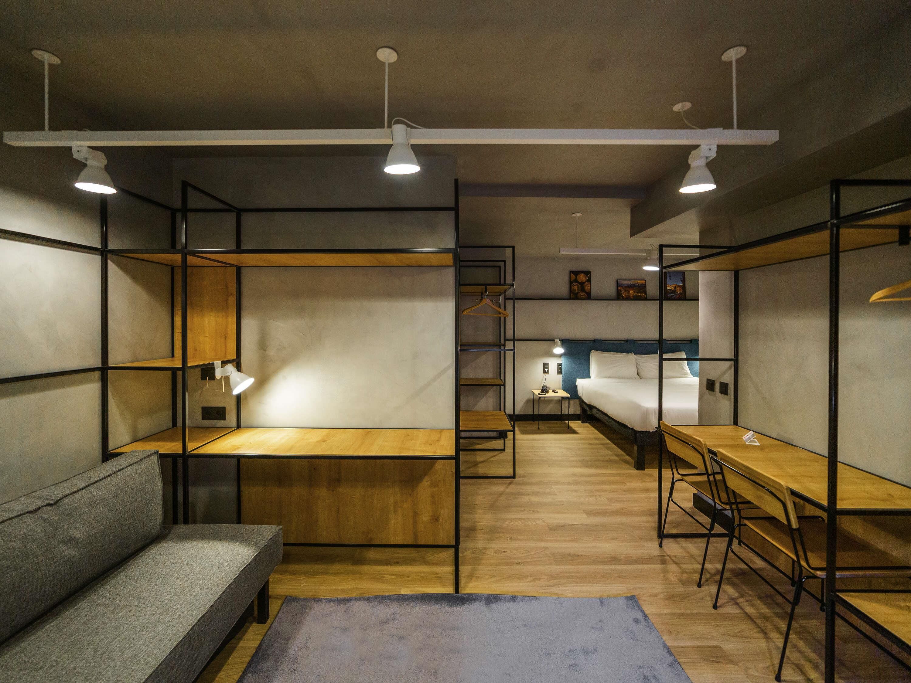 Une chambre compacte et moderne, équipée de lits superposés, d’un bureau et d’un canapé.