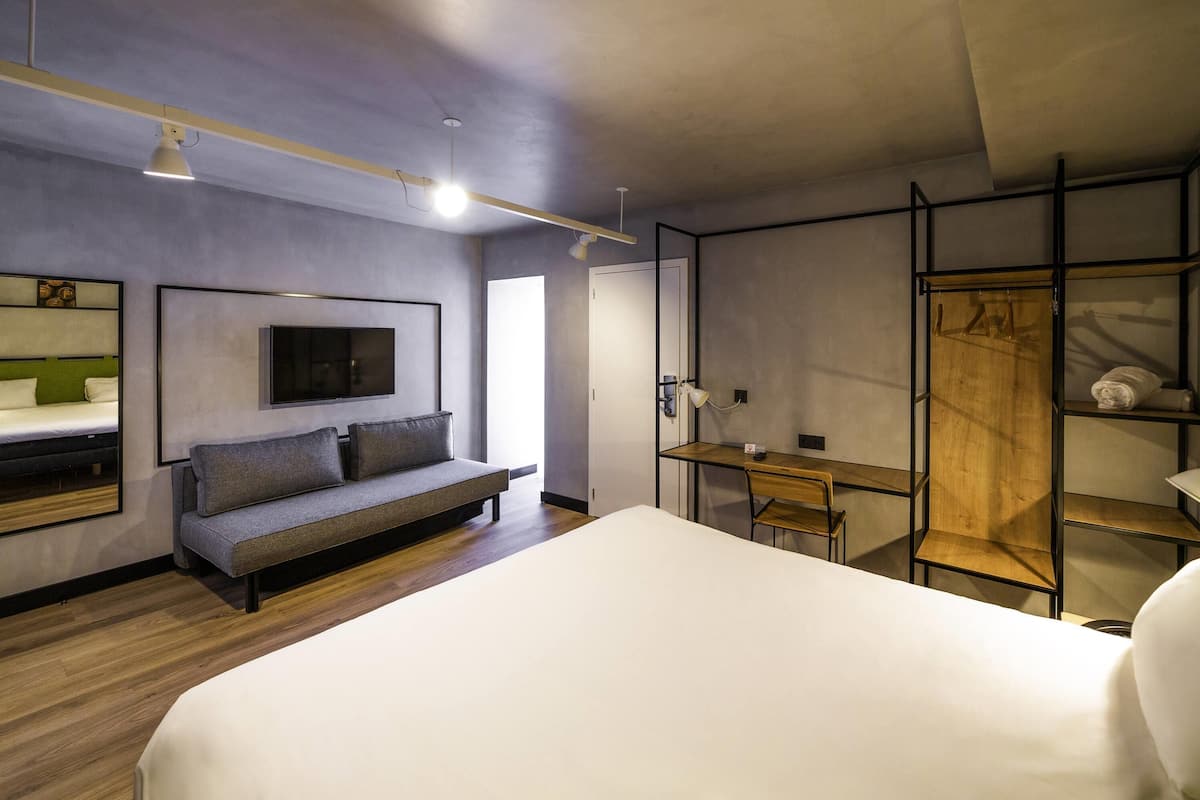 Een moderne slaapkamer met een bed, een slaapbank, een bureau en een kledingkast.