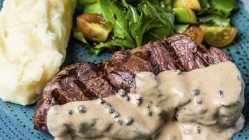 Un plato con bistec, puré de papas y ensalada.