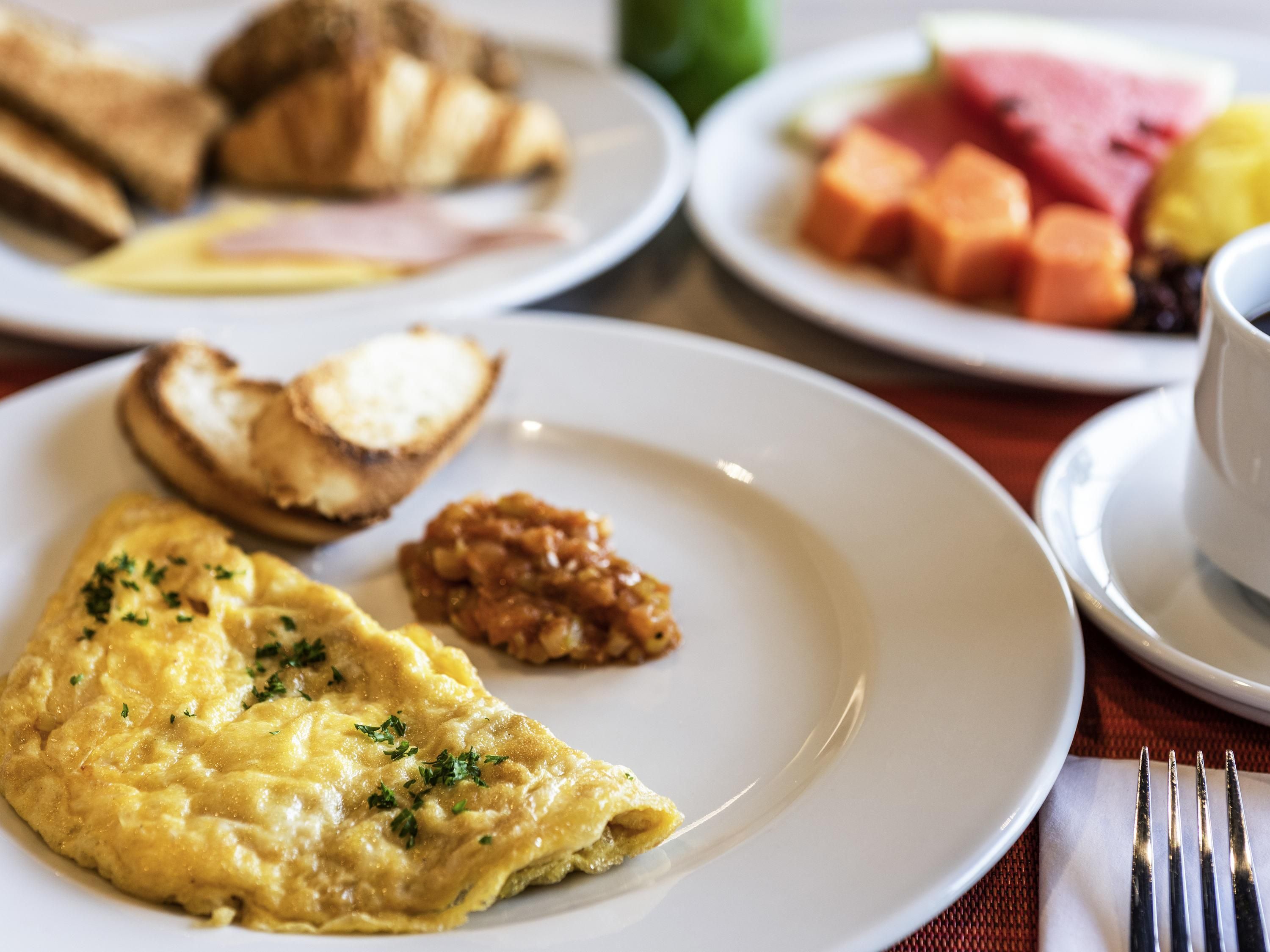 Un plato de desayuno con huevos revueltos, tostadas y un poco de mermelada.