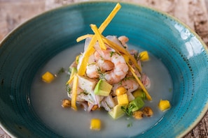 A seafood dish with shrimp, avocado, and corn in a blue bowl. - ibis Chia (Chia)