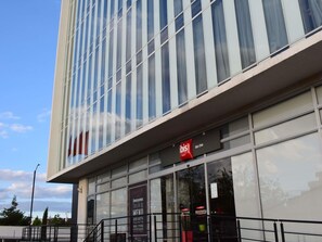 A modern hotel building with large windows and a visible sign for 'Ibis Hotel.' - ibis Chia (Chia)