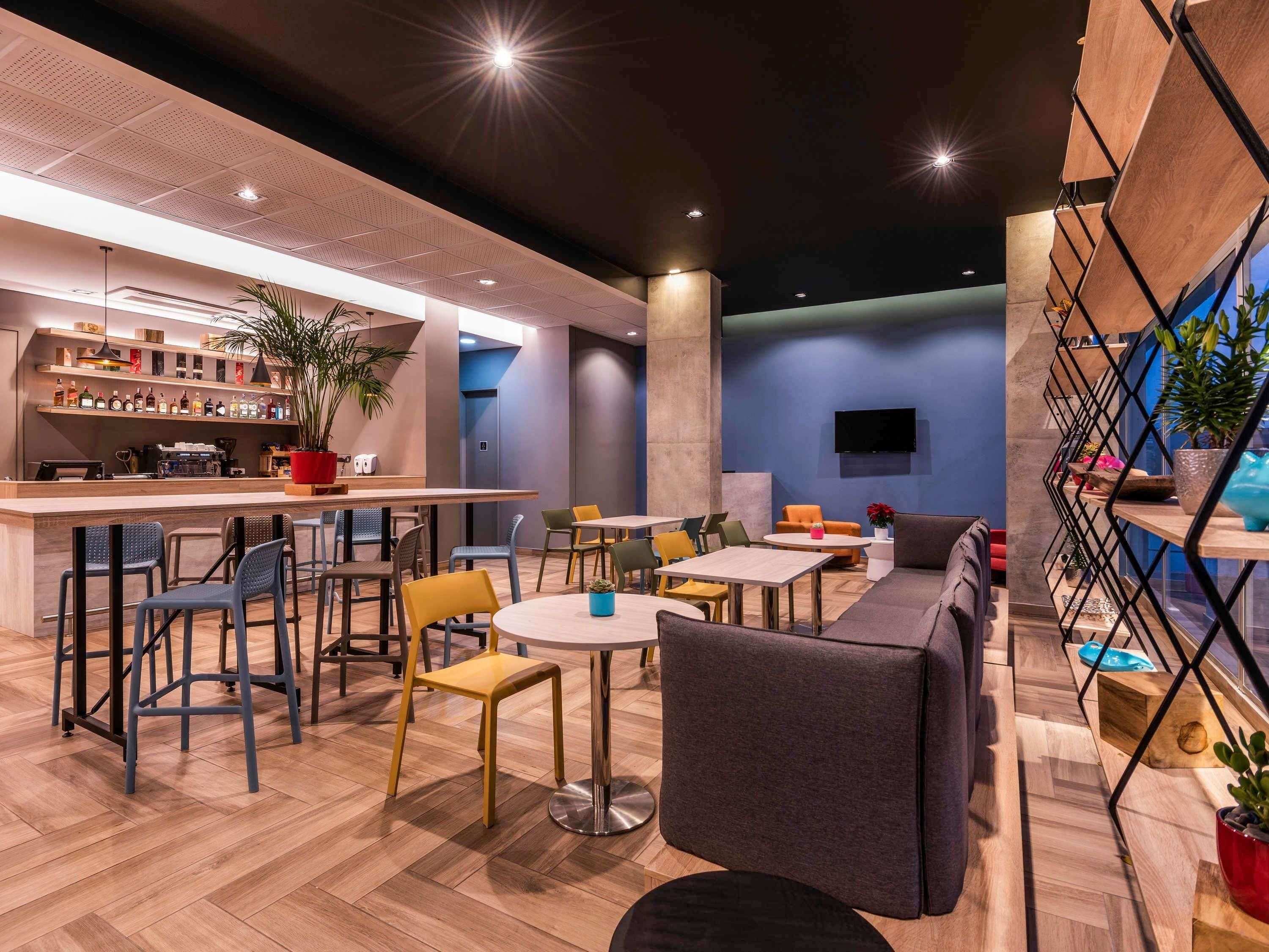 Un área de estar moderna con asientos, un bar y una pantalla de televisión.