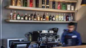 A bar area with shelves of liquor bottles, a coffee machine, and a counter. - ibis Chia (Chia)