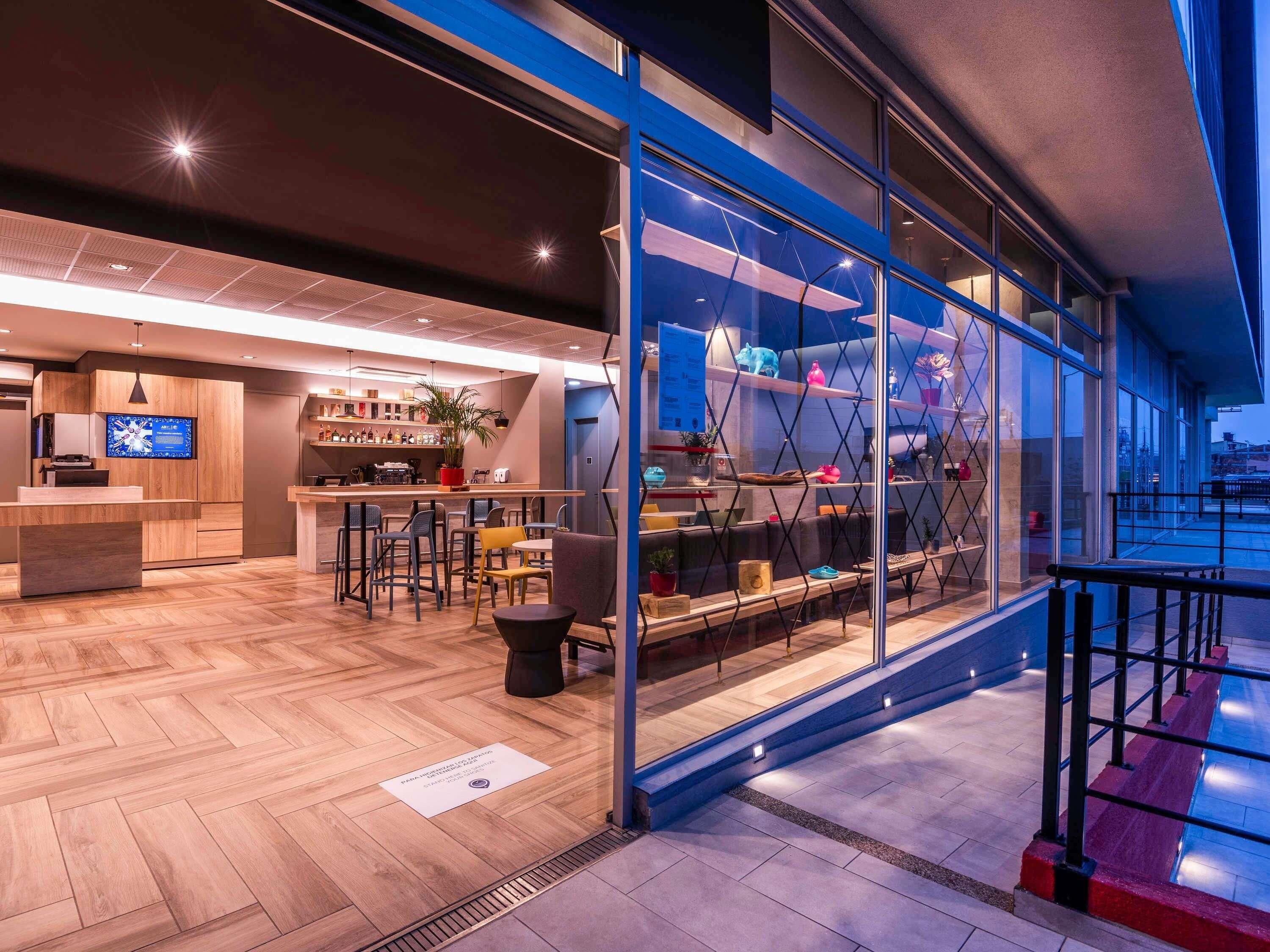 A modern interior with a bar area, seating, and a view through large windows.