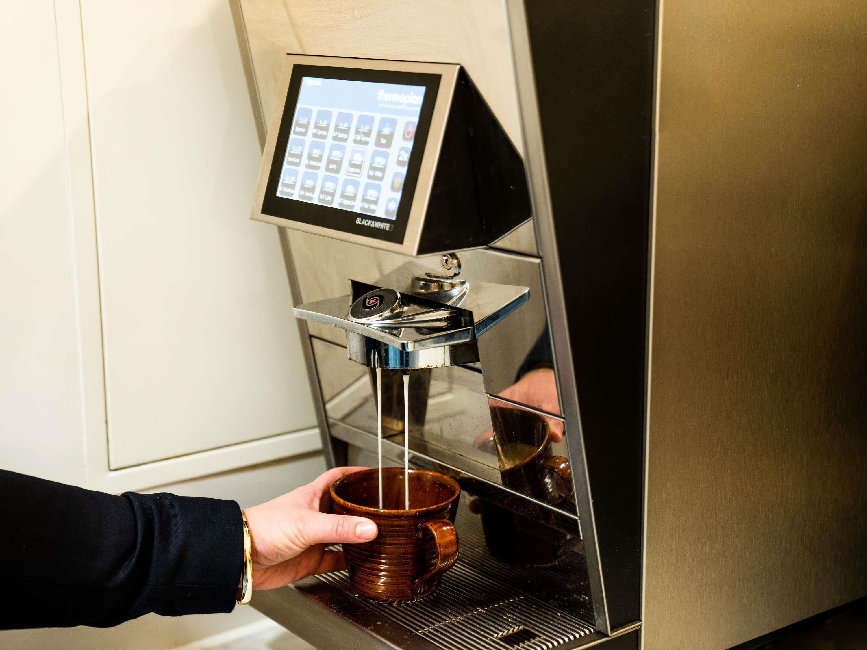 Een koffieapparaat met een touchscreen en een koffiekop die wordt gevuld.