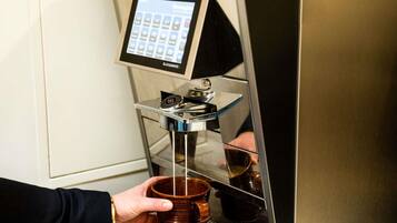 A coffee machine with a touchscreen interface and a coffee cup being filled.