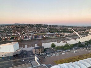 A modern building with a unique geometric roof, a parking area, and a view of a river and a bridge. - Mercure Newport Hotel (Newport)