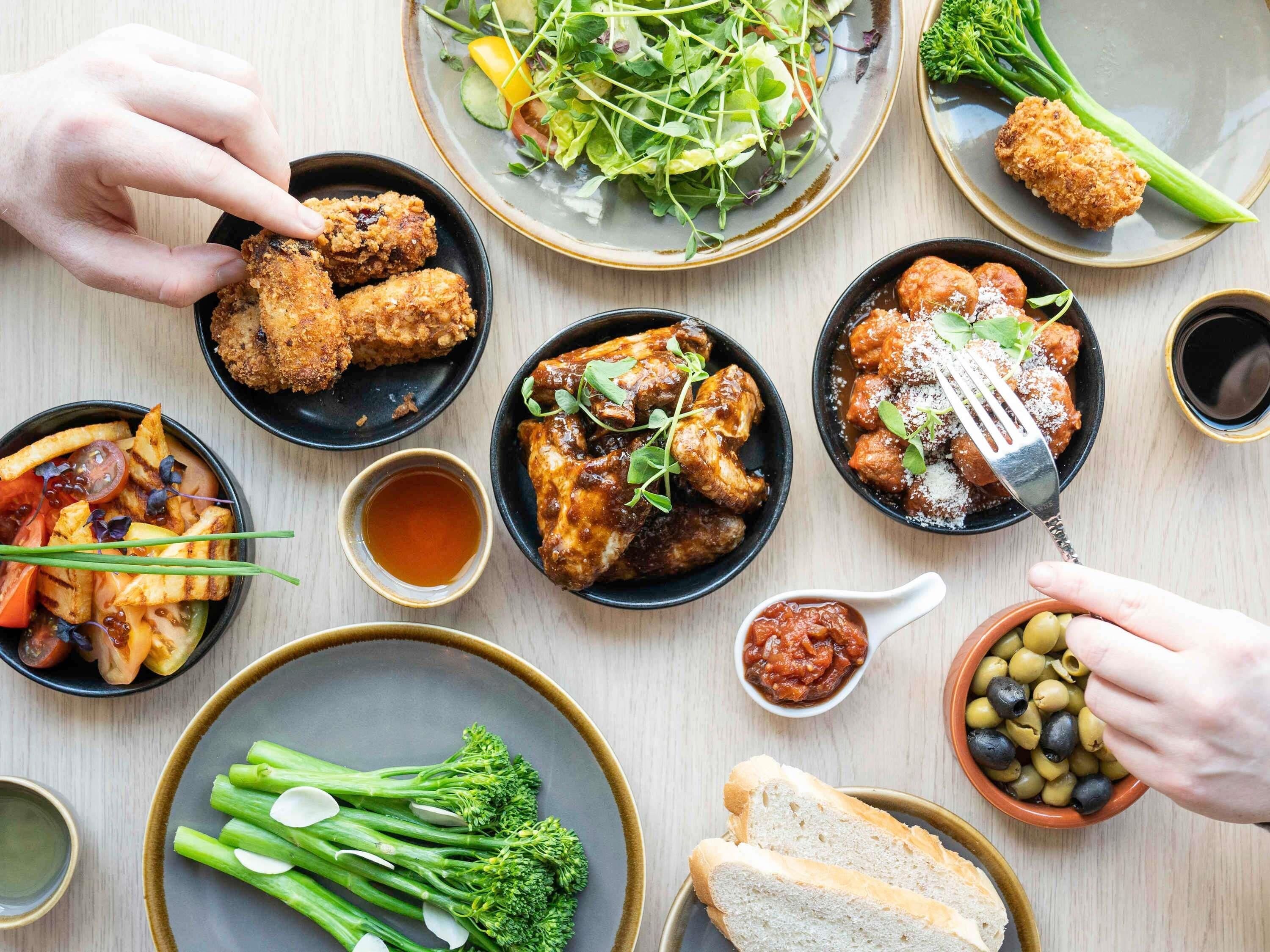 A table with various dishes including fried items, salads, and bread.