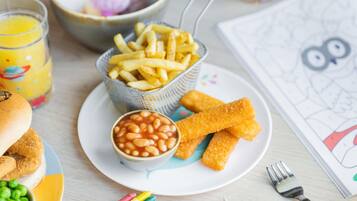A plate with French fries, baked beans, and breaded fish fingers.