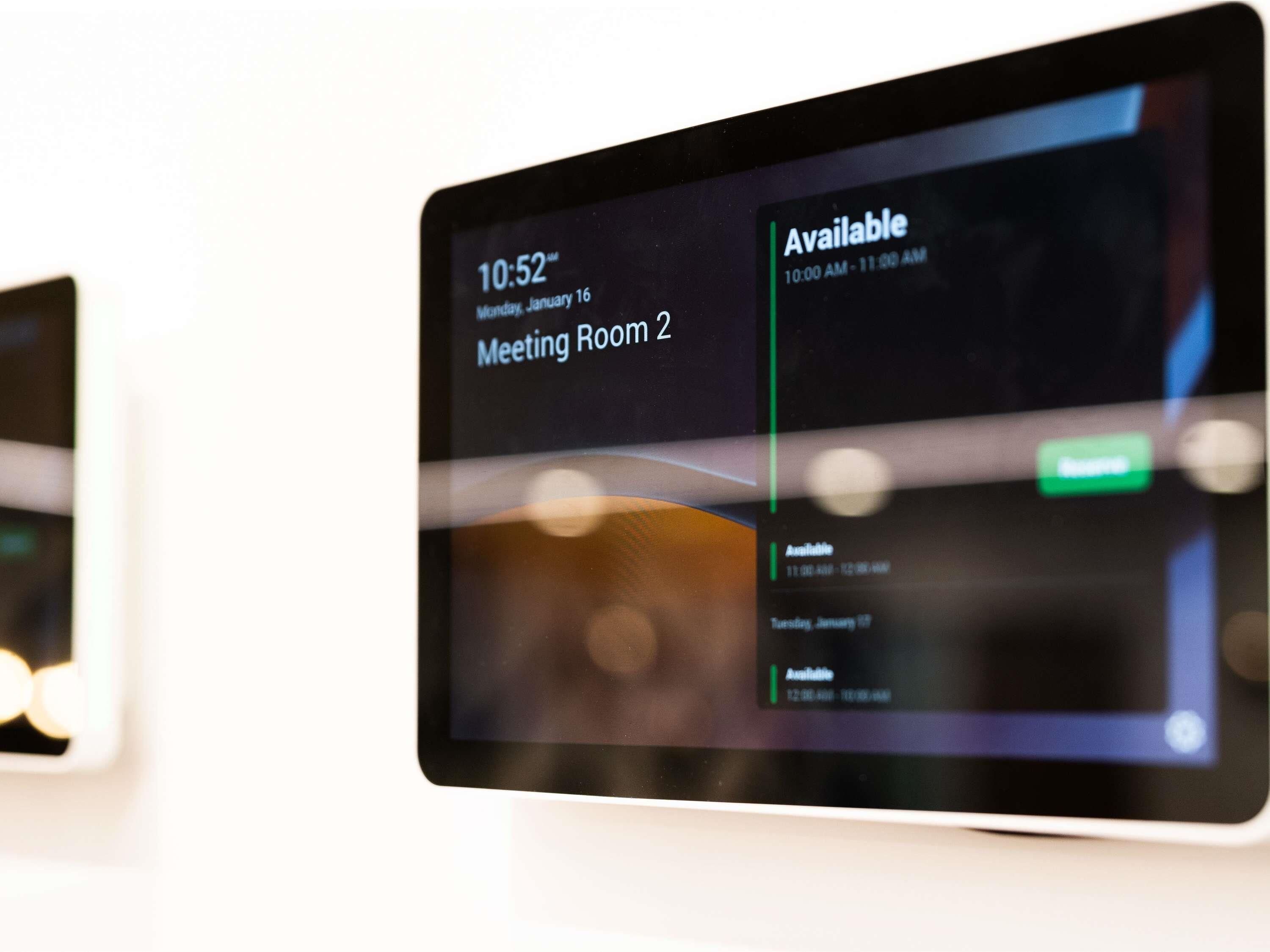 A digital display indicating Meeting Room 2 is available from 10:00 AM to 11:00 AM on Monday, January 16.