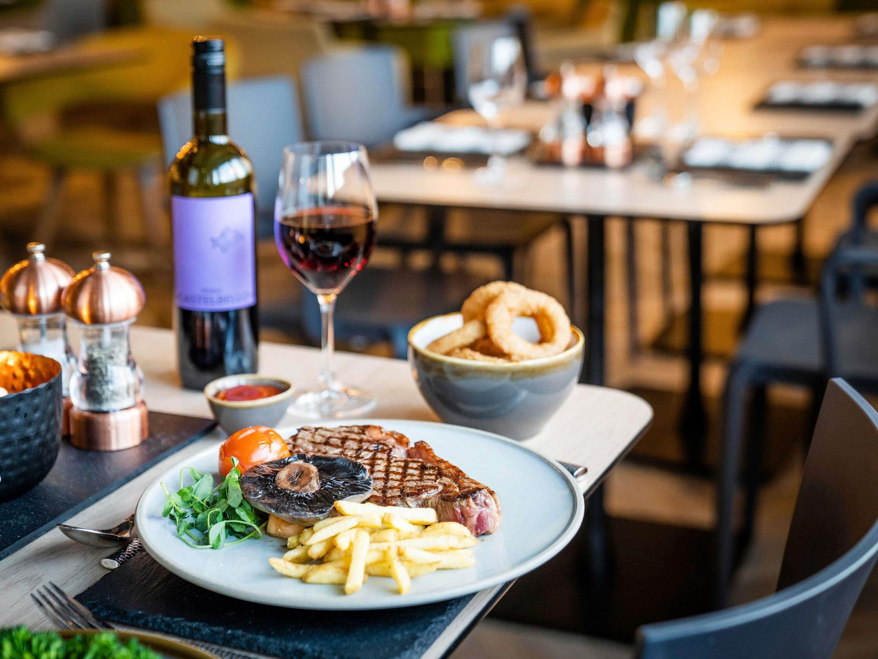 Una mesa de comedor con un plato de comida, una botella de vino y una copa de vino.