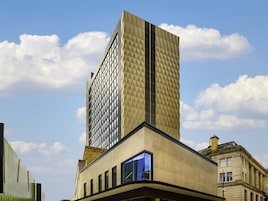 Un edificio moderno con fachada geométrica, ventanas amplias y entrada en esquina.
