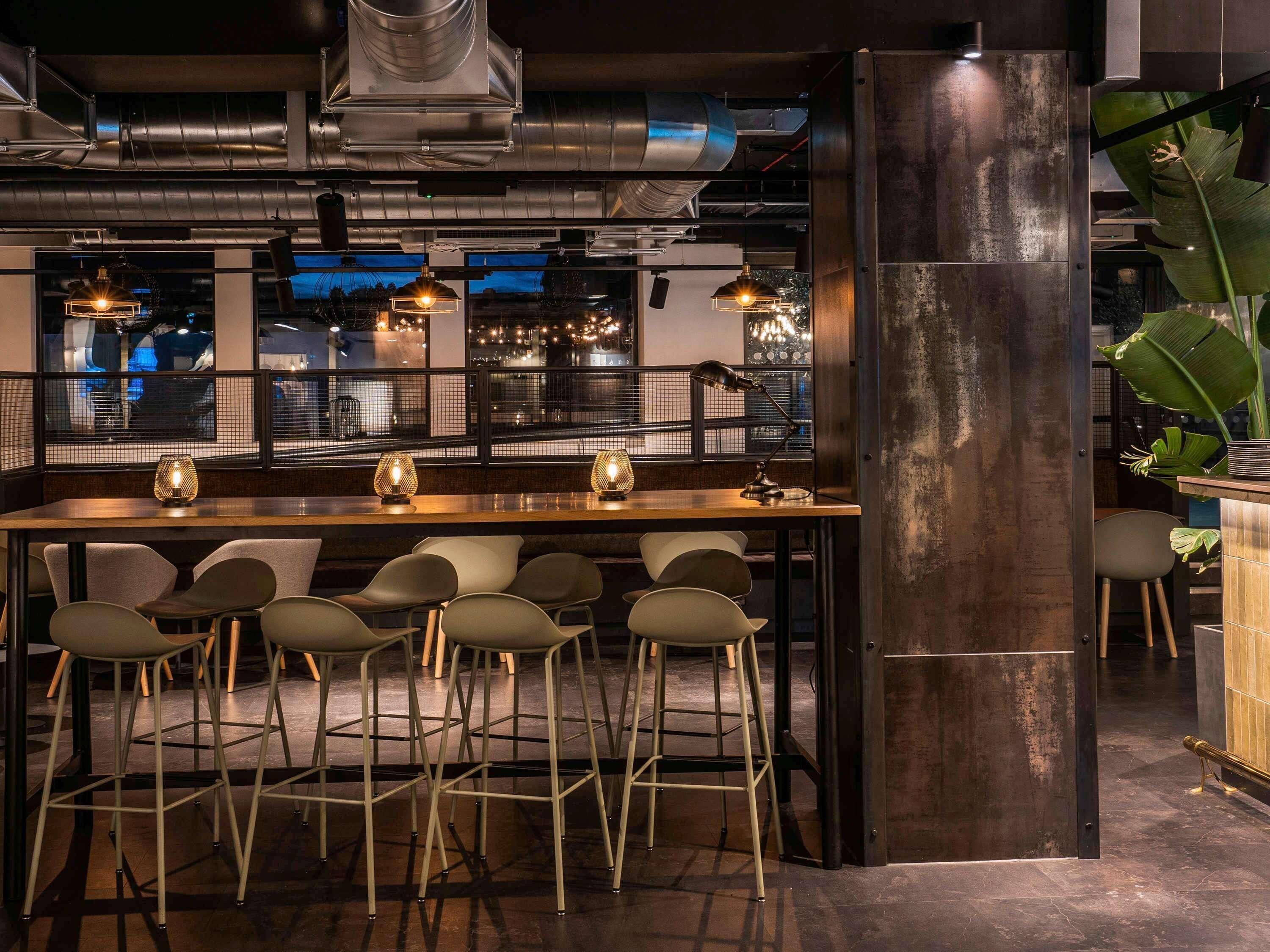 A bar area with stools, pendant lighting, and a view through a window.