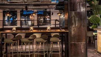 A bar area with stools, pendant lighting, and a view through a window.
