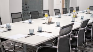 A conference room with a long table, black chairs, and glassware. - Mercure Newport Hotel (Newport)