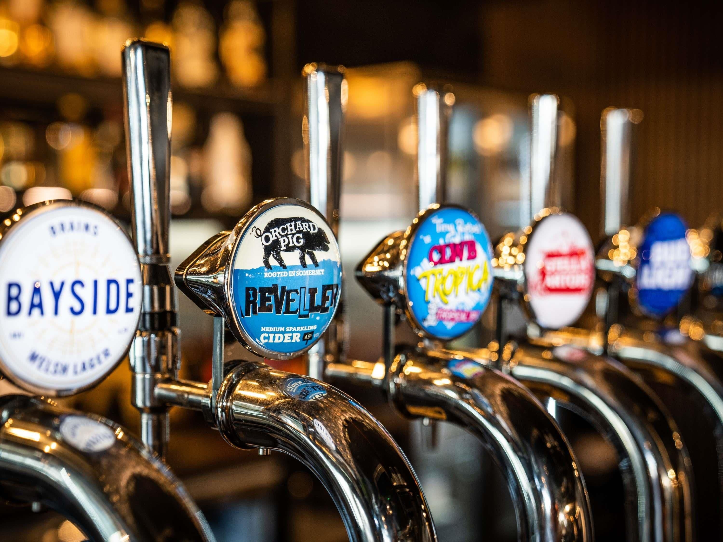 A row of beer taps with labels indicating different beer brands and types.