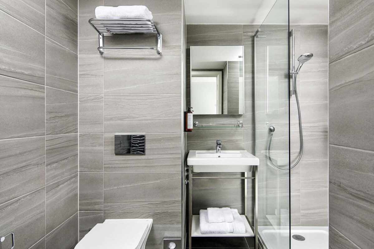 A modern bathroom with a toilet, sink, and shower area.