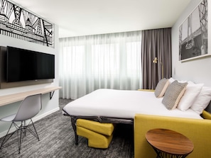 A hotel room with a bed, a desk, a TV, a chair, and a small table. - Mercure Newport Hotel (Newport)