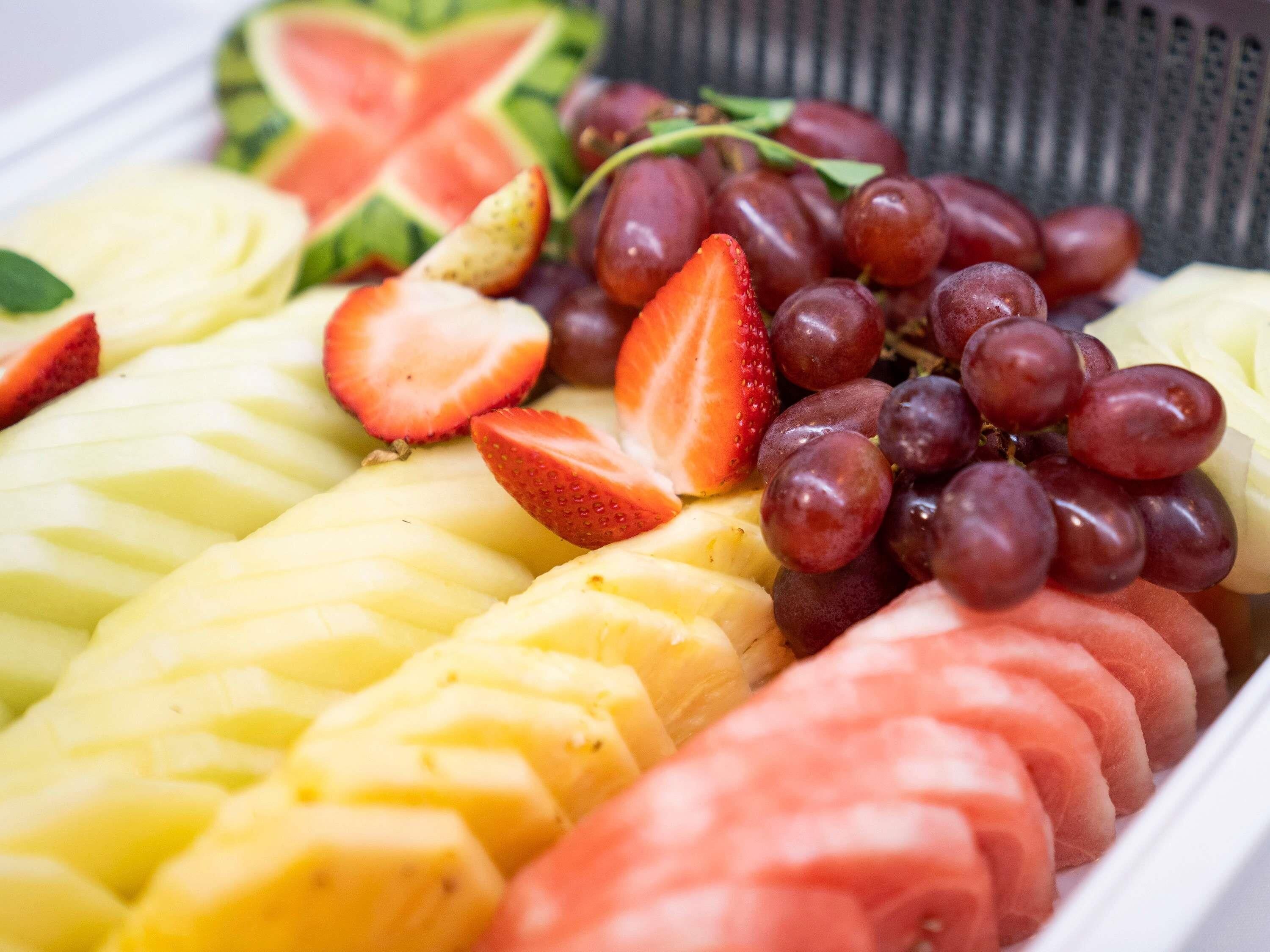 A fruit platter with sliced bananas, strawberries, and grapes.