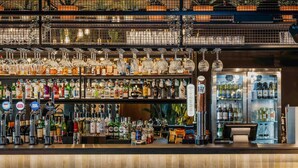 A bar area with multiple taps, shelves of bottles, and a seating area with chairs. - Mercure Newport Hotel (Newport)