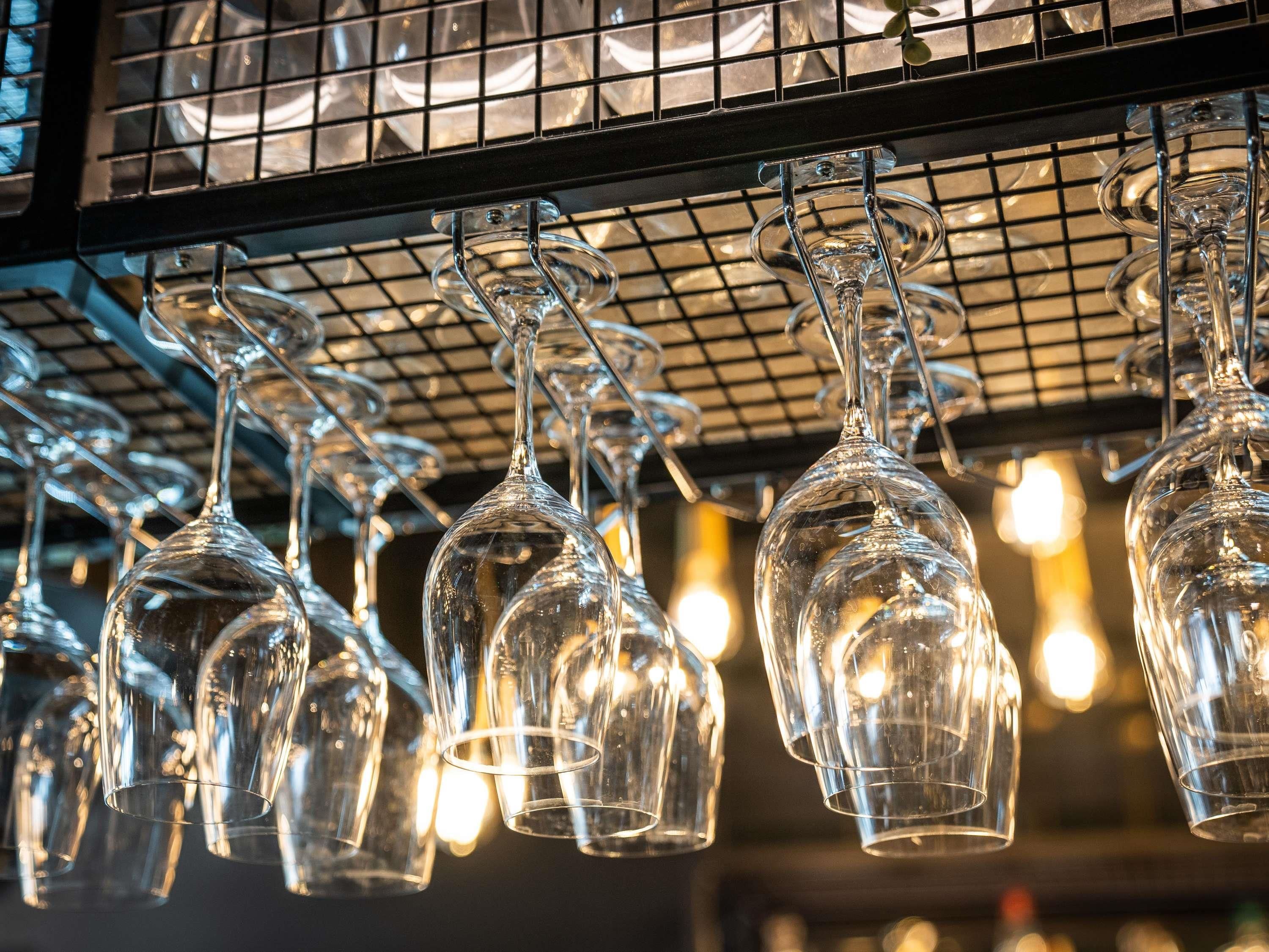 A collection of empty wine glasses hanging from a metal rack.