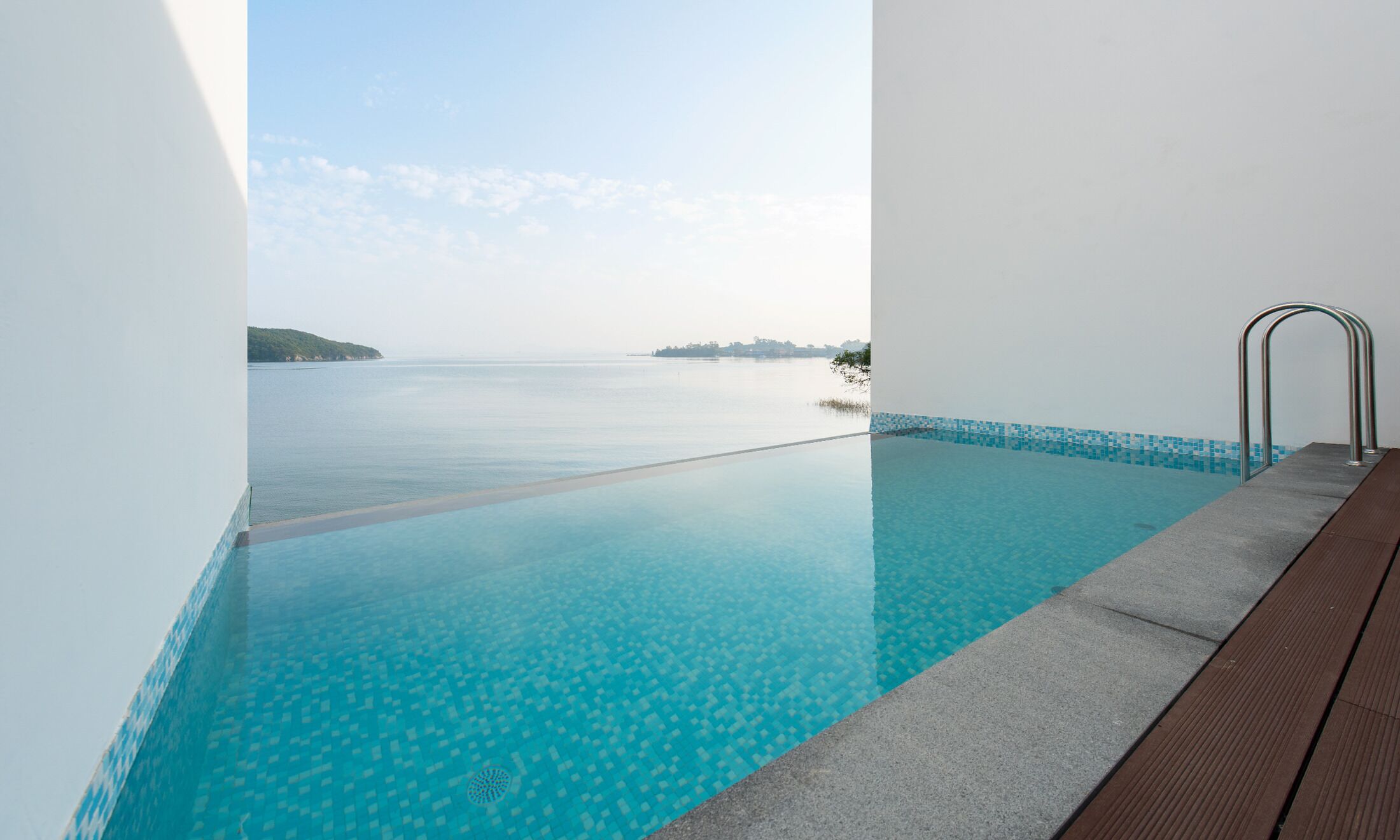 Una piscina infinita de color azul intenso con vistas al mar y a islas distantes.
