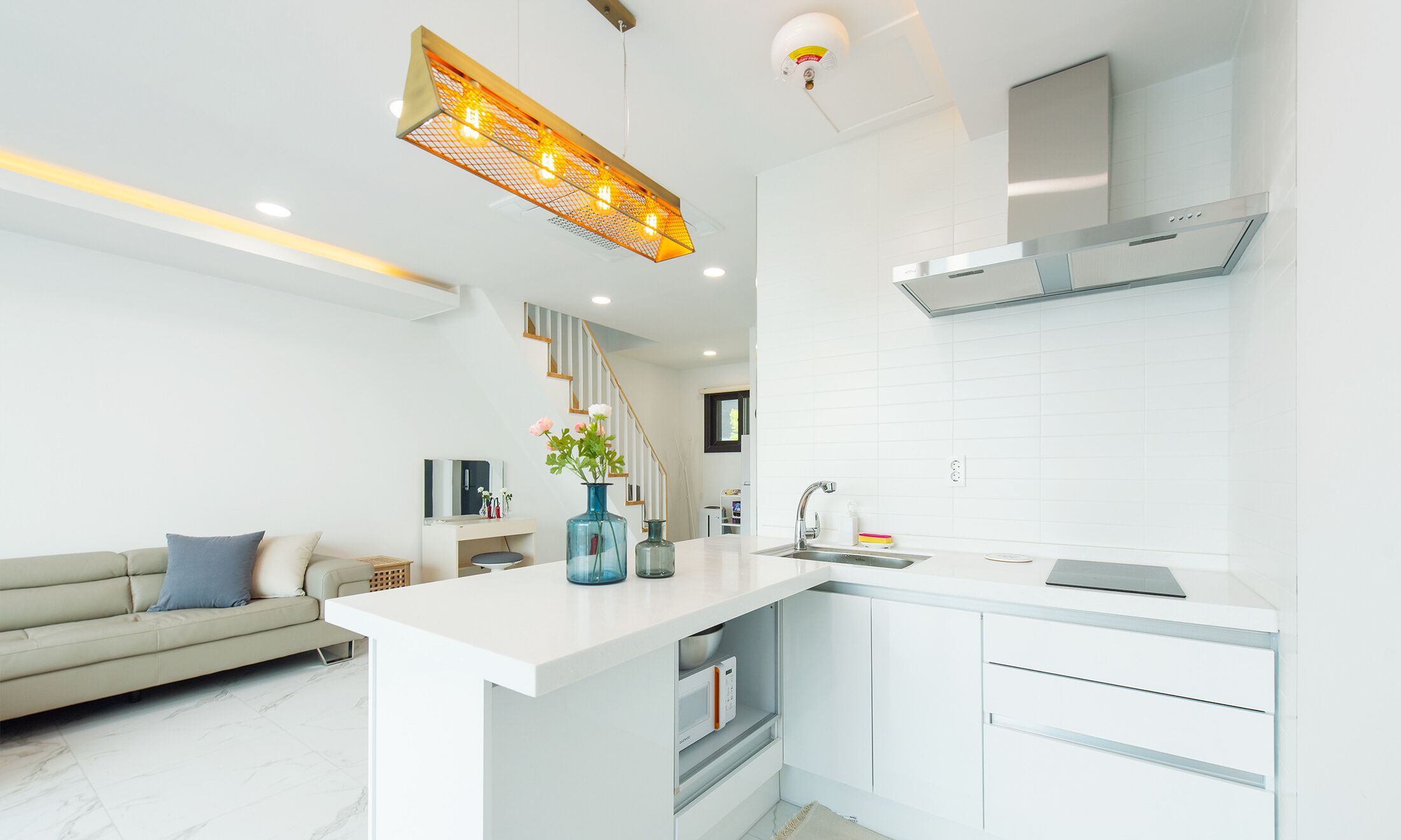 Una cocina moderna con armarios blancos, microondas integrado y campana extractora de acero inoxidable.