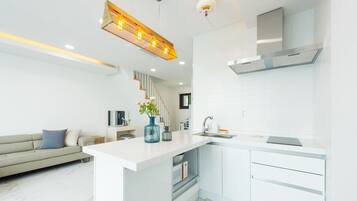 Una cocina moderna con armarios blancos, microondas integrado y campana extractora de acero inoxidable.