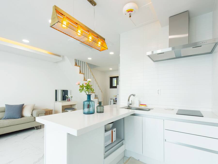 Una cocina moderna con armarios blancos, microondas integrado y campana extractora de acero inoxidable.