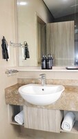 A bathroom with a white sink, a mirror, and toiletries on the counter.