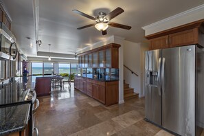 Una cocina moderna con una isla grande, electrodomésticos de acero inoxidable y vistas al océano.