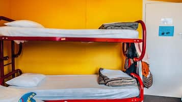 A bunk bed with two levels, a red metal frame, and a yellow wall.