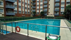 A swimming pool with a wooden deck, metal railings, and a lifebuoy.