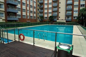 A swimming pool with a wooden deck, metal railings, and a lifebuoy.