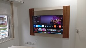 A TV mounted on a wall with a view of a pool outside.