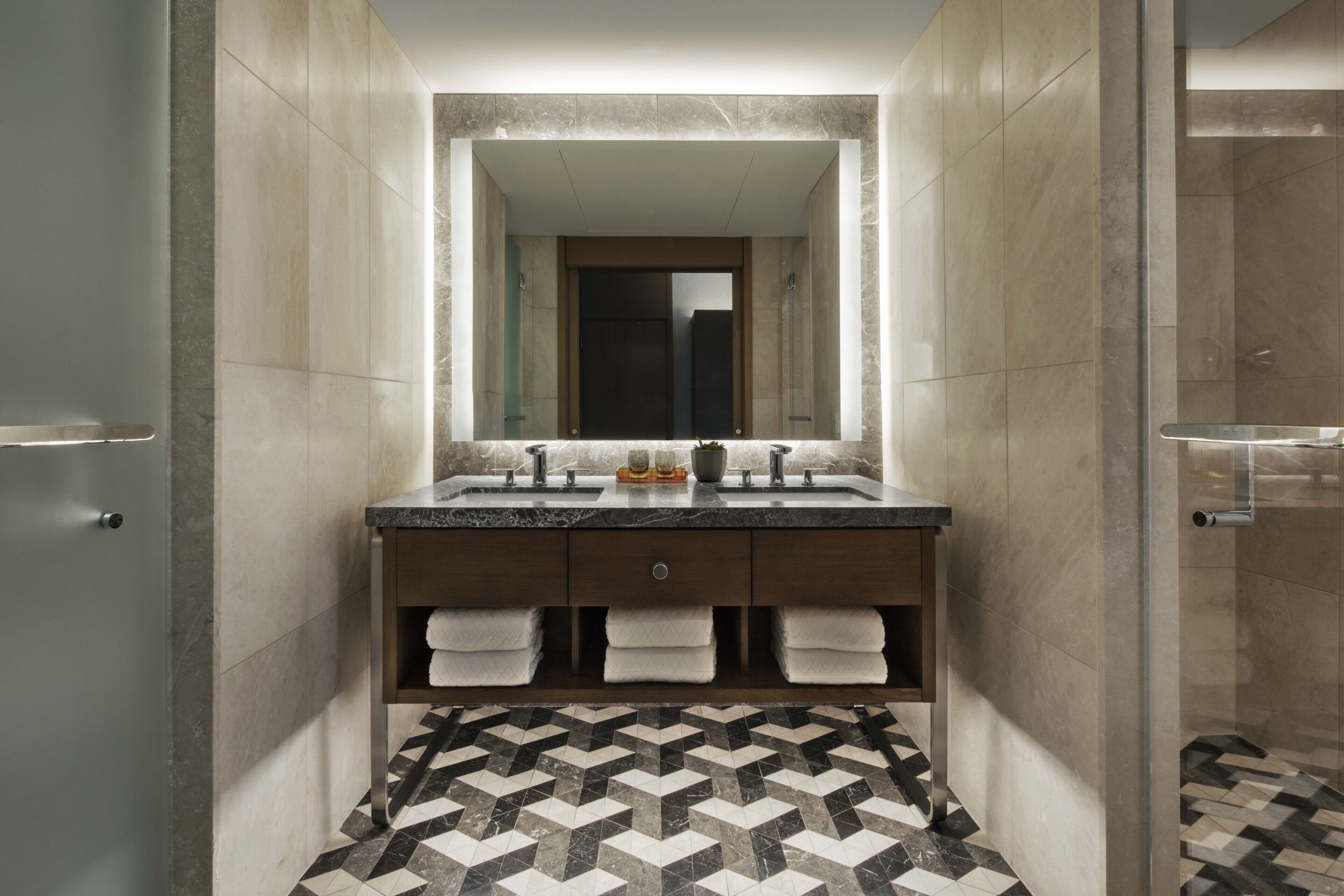 Une salle de bain moderne avec un double vasque, un grand miroir et un carrelage décoratif.
