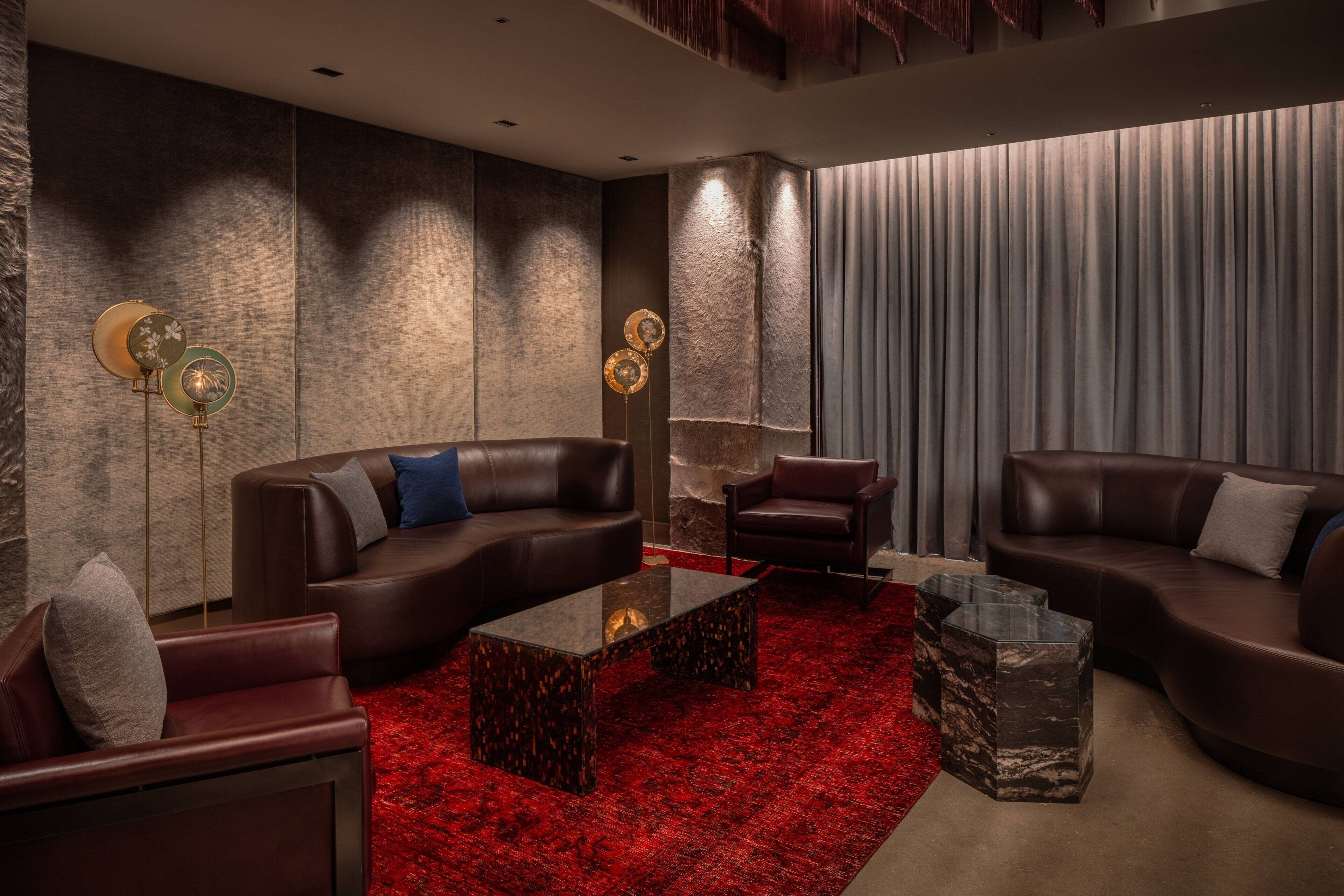 Uma sala de estar moderna com sofás de couro, um tapete vermelho e arandelas decorativas.