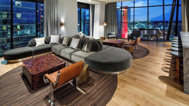 A modern living room with a sectional sofa, a patterned coffee table, and a piano. - The Joseph, a Luxury Collection Hotel, Nashville (Nashville)