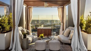 A modern balcony with a sofa, two ottomans, a small table, and a potted plant. - The Joseph, a Luxury Collection Hotel, Nashville (Nashville)